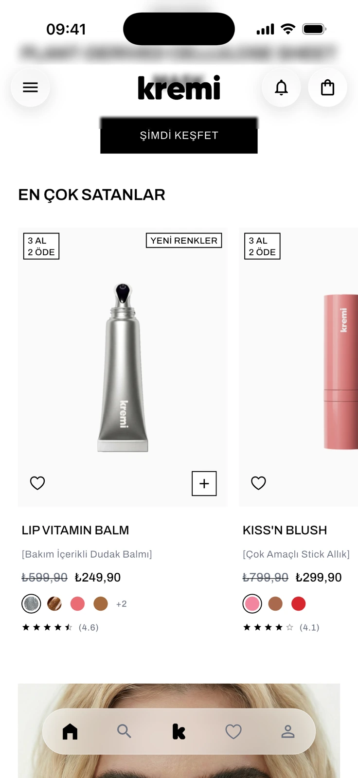 The EN ÇOK SATANLAR (best sellers) row on the home screen: Lip Vitamin Balm and Kiss'n Blush cards with 3 AL 2 ÖDE (buy 3, pay 2) and YENİ RENKLER (new shades) badges, struck-through and current prices, color dots, star ratings, and heart and plus buttons.